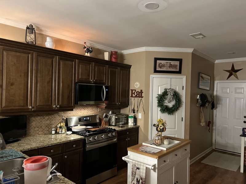 Kitchen with dark cabinets, granite counters, and a tile backsplash