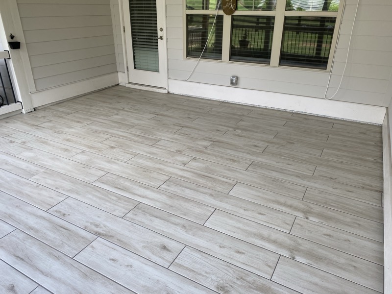 The covered porch finished with gray wood-look tile