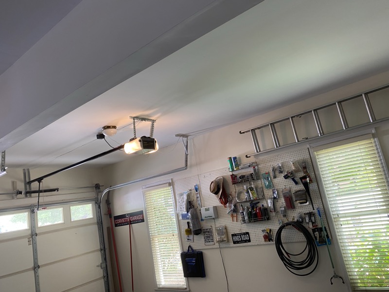 Finished garage with a smooth drywalled ceiling and organized wall