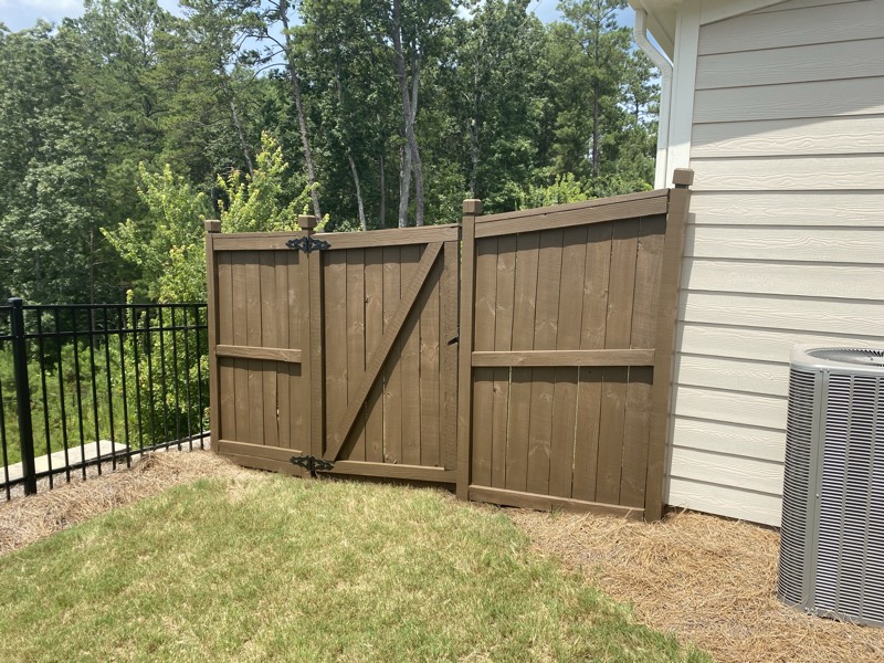 The wood fence and gate after a fresh brown stain