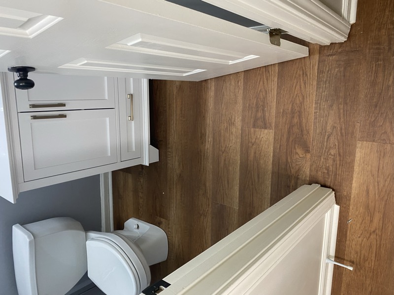 Powder room with new wood-look plank flooring and a white vanity