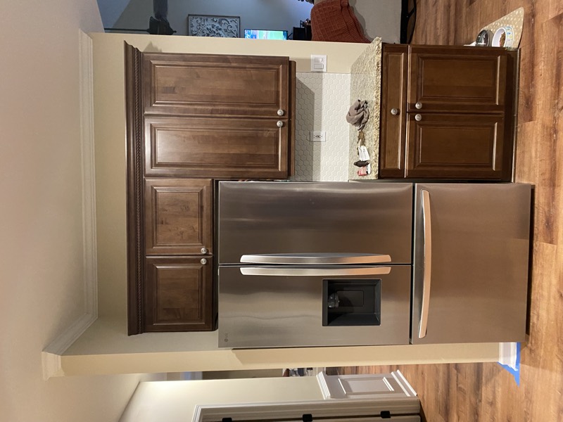 Stainless refrigerator flanked by dark cabinets with a hex-tile backsplash
