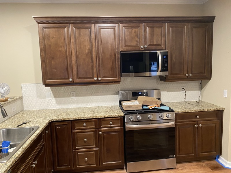 Kitchen with dark cabinets, granite counters, a range, and a white hex-tile backsplash