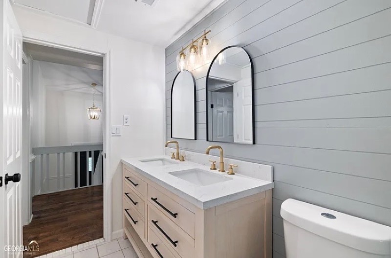 Renovated double-vanity bathroom with shiplap walls and gold fixtures