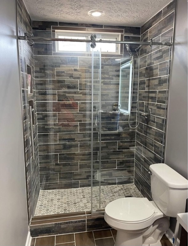 Walk-in shower with dark slate-look tile and a frameless glass door